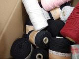 a box full of different colored yarns and spools