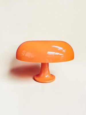 une lampe de table orange posée sur une surface blanche