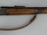 un fusil accroché au mur d'une pièce aux murs blancs