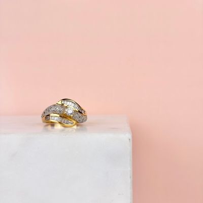 a close up of a gold and diamond ring on a marble block