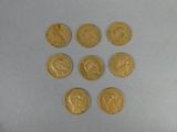 six pièces d'or sont disposées en triangle sur une surface blanche