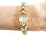 a woman ' s wrist that has a gold watch on it