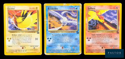 trois cartes Pokémon posées sur une table avec un fond noir