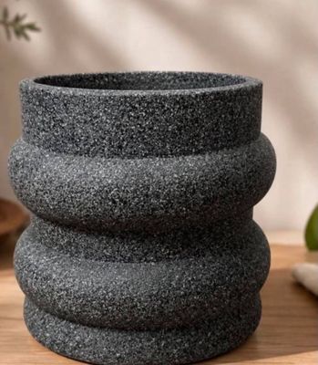a close up of a black stone vase on a wooden table