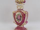 a pink vase with a gold decoration on it