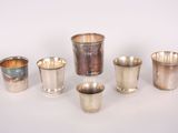 several silver cups and cups are lined up on a white surface