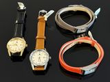 three different watches are sitting on a black surface next to each other