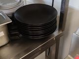 several plates and pans are stacked on a metal shelf in a kitchen