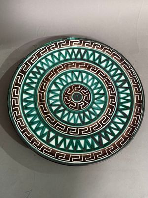 green and brown decorative plate with geometric design on white surface