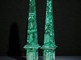 paire d'obélisques en verre vert ornés de sculptures sur un fond noir