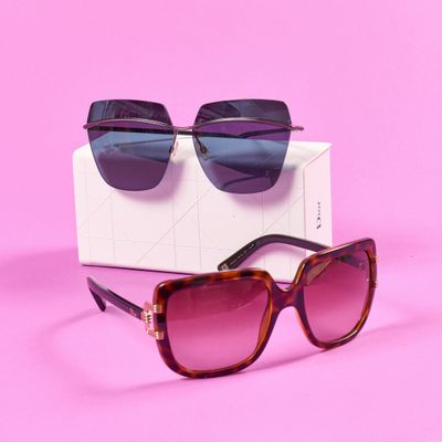 une paire de lunettes de soleil posée sur une boîte, sur une surface rose
