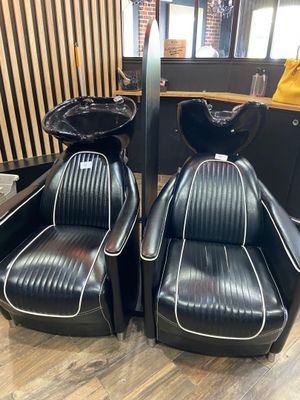 pair of black leather chairs with white trims in a salon