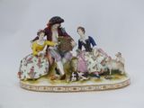 a figurine of three people sitting on a bench with a dog