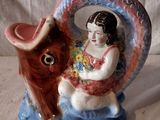 une figurine représentant une fillette assise sur un cheval