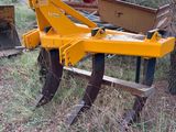 a yellow plow sitting in the grass next to a tree