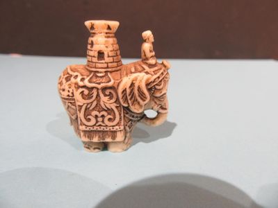 une figurine représentant un éléphant avec un homme assis dessus