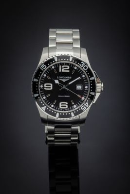 a close up of a watch on a black surface with a dark background