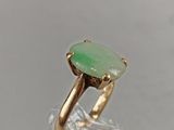 an image of a gold ring with a green stone on top of it