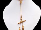 un collier en or orné d'une croix et d'un pompon, porté par un mannequin