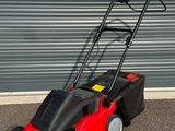 une photo d'une tondeuse à gazon rouge garée devant la porte d'un garage