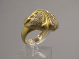 une photo d'une bague en or et diamants posée sur une surface transparente