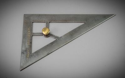 un gros plan d'un triangle métallique posé sur une surface blanche