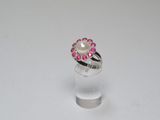 a close up of a ring with a pearl and pink stones