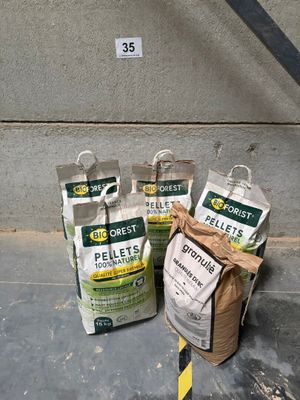 several bags of pellets sitting on the ground next to a wall