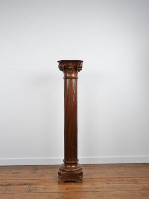 an antique wooden column stands on a hard wood floor