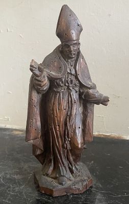 une statue représentant un homme tenant un livre posé sur une table