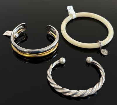 trois bracelets différents et une bague posés sur un fond noir