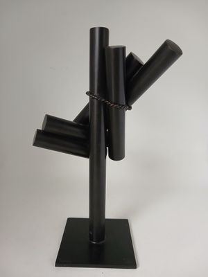 une sculpture noire composée de tubes métalliques, posée sur un socle noir