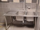 un lavabo en acier inoxydable dans une salle de bains aux murs carrelés