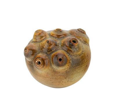 un vase marron percé de trous posé sur une surface blanche