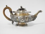 an antique silver teapot with a wooden handle on a white background