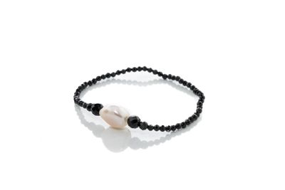 un gros plan d'un bracelet composé de perles noires et d'une perle blanche