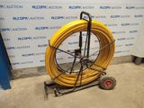 an image of a yellow hose is on a cart in front of a wall