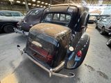 an old black car parked in a garage with other cars