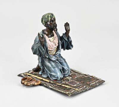 figurine of a man sitting on a rug on a white background