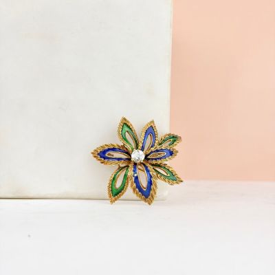 blue, green and gold flower brooch with pearls on a white surface