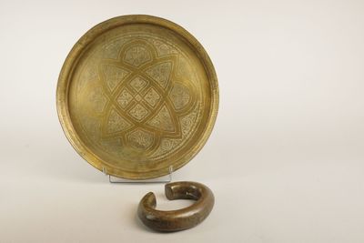 une image représentant une assiette en or posée sur un socle en bois, sur fond blanc