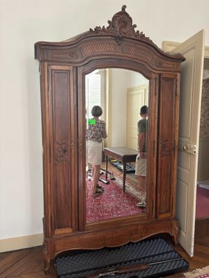 a large wooden armoire with a mirror on top of it