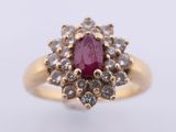 a close up of a gold ring with a ruby stone surrounded by white diamonds