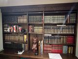 a book shelf with many books on it and a statue on top of it
