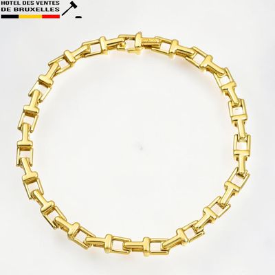 gros plan d'un bracelet en or sur une surface blanche