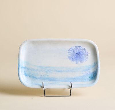 plat bleu et blanc orné d'un pissenlit, posé sur un socle