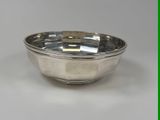 a silver bowl on a white table with a green background