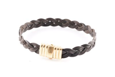 un gros plan sur un bracelet tressé noir muni d'un fermoir doré