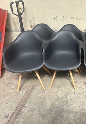 four black plastic chairs with wooden legs sitting in a room