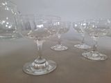 four wine glasses and a pitcher sitting on a table